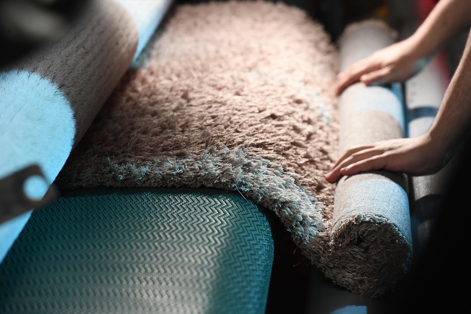 Hands carefully inspecting a rug at Poly Service
